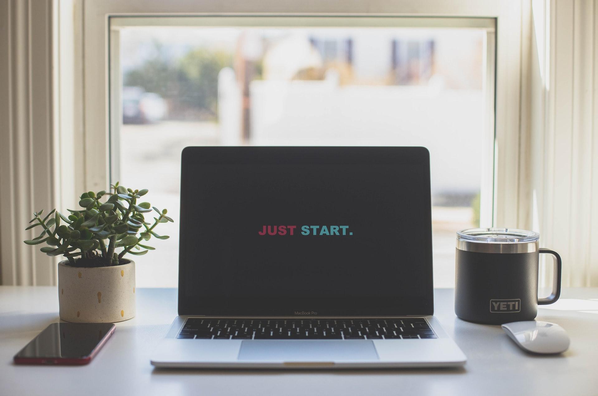 Laptop with wallpaper that says just start